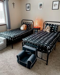 two twin beds with black and white bedding in a bedroom next to a couch