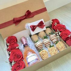 a box filled with lots of different types of food and flowers next to a bottle of booze