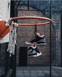 two pairs of shoes hanging from a basketball hoop