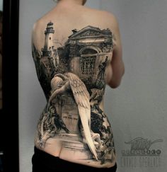 the back of a woman's body is covered in tattoos and features an image of a lighthouse