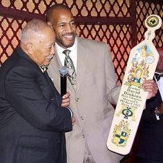 two men standing next to each other holding an award