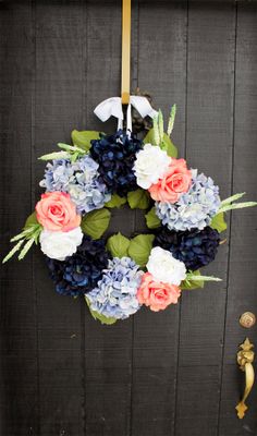 a wreath is hanging on the door with blue and pink flowers in it, along with greenery