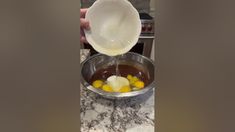 a person pouring milk into a bowl filled with eggs