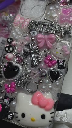 a hello kitty phone case with lots of different charms on it's back cover