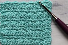 a crochet square with a knitting needle next to it