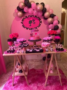 a table topped with lots of pink and black desserts