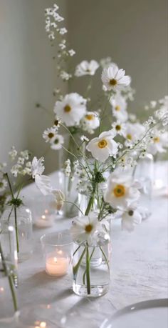 there are many vases with flowers in them on the dining room table, one is filled with candles