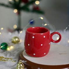 a red coffee cup sitting on top of a table next to christmas decorations and lights