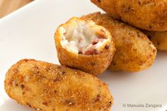 some fried food on a white plate with cheese and sauce in the middle, ready to be eaten