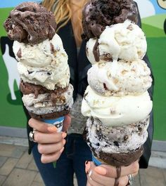 a woman holding two ice cream cones in her hands