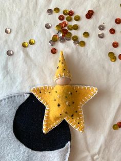 a felt star ornament sitting on top of a piece of fabric next to confetti