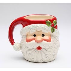 a ceramic mug with a santa clause on it's face and holly berry decoration