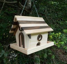 a bird house hanging from a chain in the woods