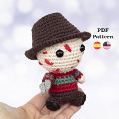 a small crocheted doll wearing a hat and holding it in the palm of someone's hand