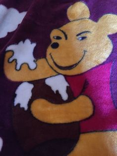 a winnie the pooh towel is laying on top of a purple and white blanket