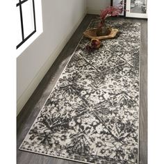 a white and black area rug with an ornate design on the floor next to a window