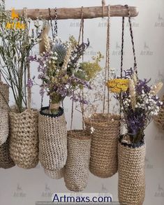 several vases filled with different types of flowers hanging from a wooden beam in front of a white wall