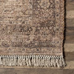 an area rug with fringes on top of it and wood flooring in the background