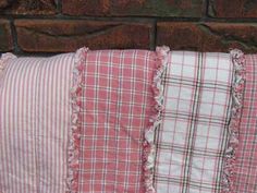 four pillows are lined up against a brick wall, one is pink and the other is white