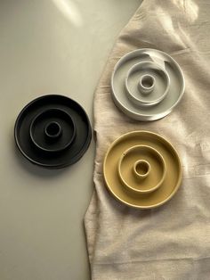 three plates sitting on top of a table next to each other, one black and one gold