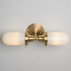 a bathroom light that has two lights on each side of the wall and is gold