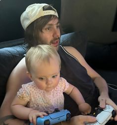 a man sitting next to a baby holding a game controller