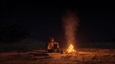 two people sitting around a campfire at night