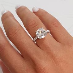 a woman's hand with a diamond ring on top of her finger and an engagement band