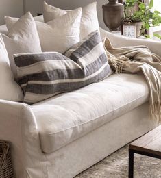 a white couch with pillows and blankets on it