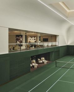 an indoor tennis court with chairs and tables in the center is lit by recessed lighting