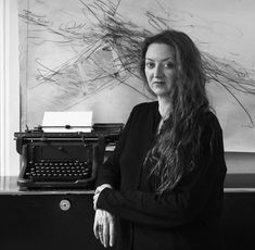 a woman standing in front of an old typewriter