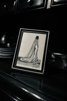 a black and white photo of a woman in a wedding dress on a table with plates