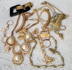 a bunch of different types of necklaces on a white cloth with gold chains and charms