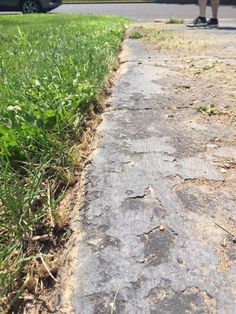 a person walking down a sidewalk next to grass