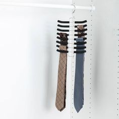 three ties hanging from hooks on a white wall in a store or office area, one is black and the other is brown