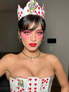 a woman in a white dress with red hearts on her face and wearing a crown