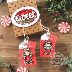 two christmas tags hanging from a wooden table next to candy canes and peppermint