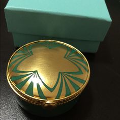 a green and gold box sitting on top of a table next to a blue box