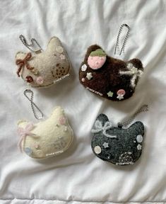 four little purses are sitting on a bed together, one has a cat and the other is a dog