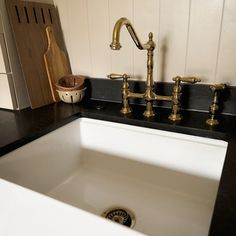 a white sink sitting under a faucet next to a wooden cutting board