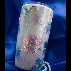 a frosted glass vase with snowflakes on it and beads around the rim