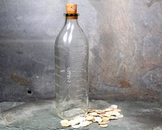 a bottle filled with almonds sitting on top of a stone floor next to a wall