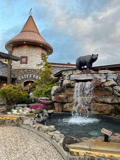 a bear statue sitting on top of a waterfall next to a building