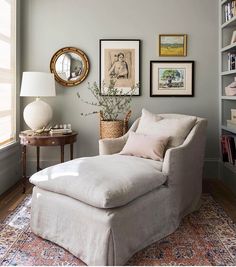 a living room with a chair, ottoman and pictures on the wall above it's bookshelf