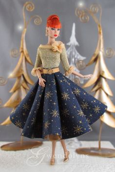 a doll with red hair wearing a blue dress and gold shoes in front of christmas trees