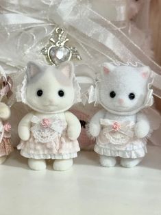 three little white kittens dressed up in pink and white dresses, one wearing a tiara