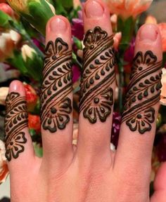 a woman's hand with henna tattoos on it and flowers in the background