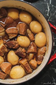 a pot filled with meat and potatoes on top of a stove