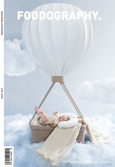 a baby laying on top of a basket in the clouds with a hot air balloon above it