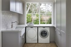 a washer and dryer in a small room with an open window over the sink